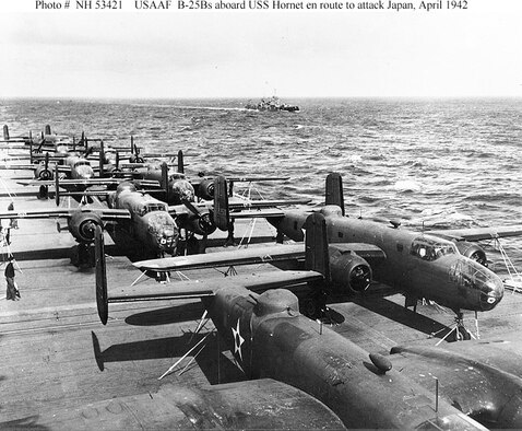 View from the island of USS Hornet (CV-8), while en route to the mission's launching point. USS Nashville (CL-43) is in the distance. Eight of the mission's 16 B-25B bombers are visible on the carrier's flight deck. Aircraft at right is tail No. 40-2250 and mission plane No. 10. 2nd Lt. Richard O. Joyce piloted the aircraft to targets in the Tokyo area. (U.S. Navy photo)
