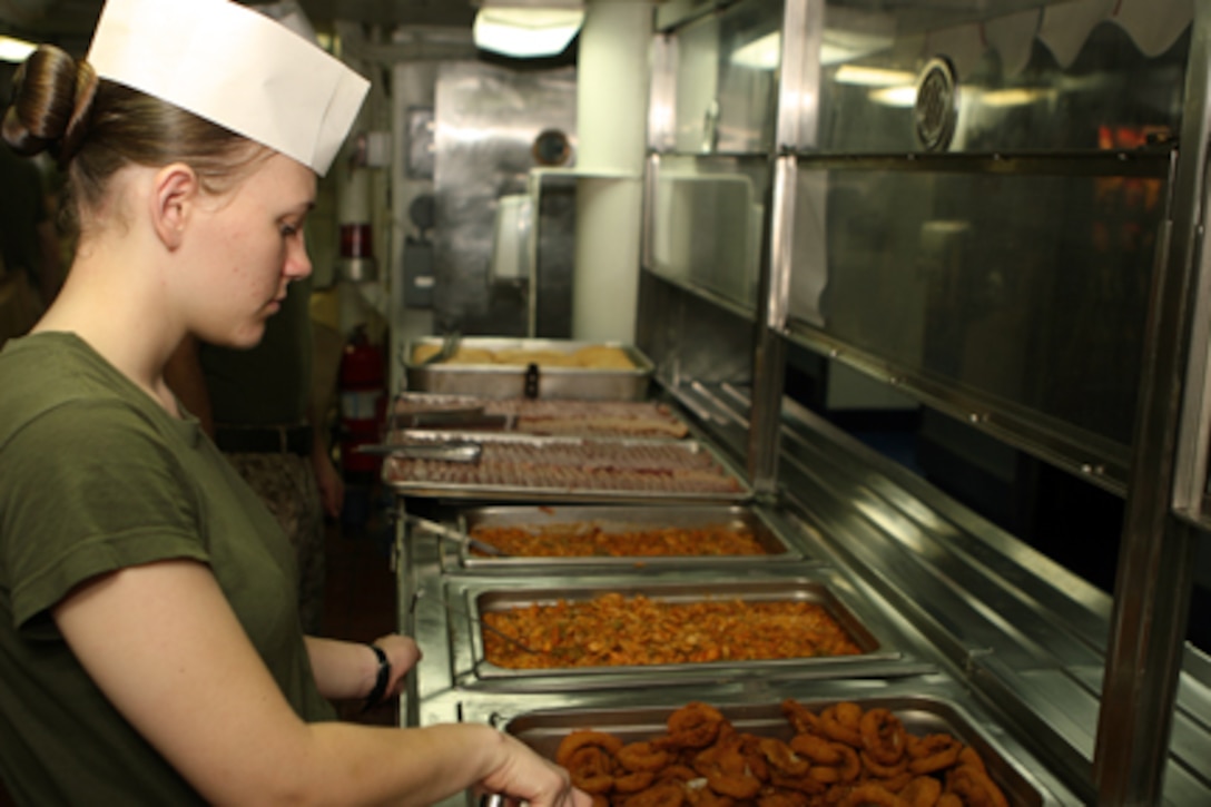 Pfc. Stephanie M. Nielsen, a maintenance administration Marine with Marine Medium Helicopter Squadron-165 (REIN), 15th Marine Expeditionary Unit prepares to serve lunch to Marines of the 15th MEU and the crew of USS Peleliu in the galley of the enlisted mess deck aboard ship.::r::::n::   The Marines and Sailors who make the mess decks run smoothly are the mess-men who prepare and serve nearly 2,400 trays per meal 4-times a day. ::r::::n::    On average, the mess-men use over 1,000 pounds of meat or poultry per meal and over a ton of fruits and vegetables per day.::r::::n::    Mess duty consists of 30 12-hour days on one of USS Peleliu's three mess decks. Mess-men help prepare, serve and store food aboard USS Peleliu as well as keeping the mess decks clean.::r::::n::   The Camp Pendleton, Calif. based 15th MEU is comprised of approximately 2,200 Marines and Sailors and is a forward deployed force of readiness capable of conducting numerous operations, such as Non-Combatant Evacuation Operations, Humanitarian Assistance Operations and a wide range of amphibious missions. The 15th MEU is currently deployed aboard the USS PELELIU (LHA-5), USS DUBUQUE (LPD-8) and USS PEARL HARBOR (LSD-52). (Official US Marine Corps photo by Lance Cpl Timothy T. Parish) (Released)