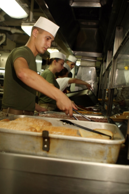 Lance Cpl. Kevin R. Sullivan, field artilleryman, India Battery, Battalion Landing Team 2/5, 15th Marine Expeditionary Unit serves lunch to Marines of the 15th MEU and the crew of USS Peleliu in the galley of the enlisted mess deck aboard ship.::r::::n::   The Marines and Sailors who make the mess decks run smoothly are the mess-men who prepare and serve nearly 2,400 trays per meal 4-times a day. ::r::::n::    On average, the mess-men use over 1,000 pounds of meat or poultry per meal and over a ton of fruits and vegetables per day.::r::::n::    Mess duty consists of 30 12-hour days on one of USS Peleliu's three mess decks. Mess-men help prepare, serve and store food aboard USS Peleliu as well as keeping the mess decks clean.::r::::n::   The Camp Pendleton, Calif. based 15th MEU is comprised of approximately 2,200 Marines and Sailors and is a forward deployed force of readiness capable of conducting numerous operations, such as Non-Combatant Evacuation Operations, Humanitarian Assistance Operations and a wide range of amphibious missions. The 15th MEU is currently deployed aboard the USS PELELIU (LHA-5), USS DUBUQUE (LPD-8) and USS PEARL HARBOR (LSD-52). (Official US Marine Corps photo by Lance Cpl Timothy T. Parish) (Released)