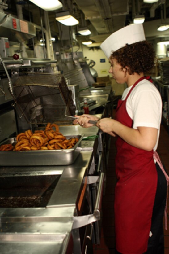 Seaman Apprentice Edaline Laporte, a cullinary specialist aboard USS Peleliu, prepares onion rings for lunch in the galley of the enlisted mess deck aboard ship.::r::::n::   The Marines and Sailors who make the mess decks run smoothly are the mess-men who prepare and serve nearly 2,400 trays per meal 4-times a day. ::r::::n::    On average, the mess-men use over 1,000 pounds of meat or poultry per meal and over a ton of fruits and vegetables per day.::r::::n::    Mess duty consists of 30 12-hour days on one of USS Peleliu's three mess decks. Mess-men help prepare, serve and store food aboard USS Peleliu as well as keeping the mess decks clean.::r::::n::   The Camp Pendleton, Calif. based 15th MEU is comprised of approximately 2,200 Marines and Sailors and is a forward deployed force of readiness capable of conducting numerous operations, such as Non-Combatant Evacuation Operations, Humanitarian Assistance Operations and a wide range of amphibious missions. The 15th MEU is currently deployed aboard the USS PELELIU (LHA-5), USS DUBUQUE (LPD-8) and USS PEARL HARBOR (LSD-52). (Official US Marine Corps photo by Lance Cpl Timothy T. Parish) (Released)