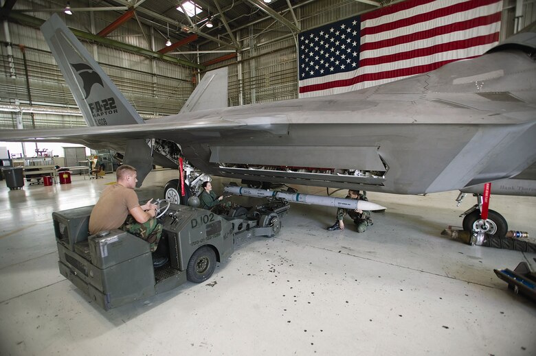 EDWARDS AIR FORCE BASE, Calif. - Senior Airman Daniel Myers, Staff Sgt. Daphne Jaehn and Staff Sgt. John Davenport load an AIM-120D Advanced Medium Range Air-to-Air Missile on an F-22A Raptor recently in preparation for noise and vibration testing here. The Airmen are all part of the 412th Aircraft Maintenance Squadron and are assigned to the F-22 Combined Test Force weapons flight. (Air Force photo by Kevin Robertson)

