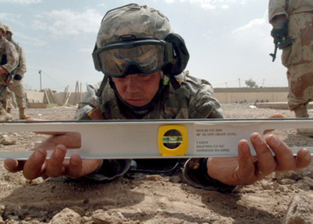 U.S. Army Spc. Gregory Carter, a member of Delta Company, 3rd Battalion, 172nd Infantry Regiment, uses a level during the construction of a playground set at a school in Abraham Jaffas, Iraq, on April 16, 2006. Big Toys, Inc., an American company, donated the playground set to the children of Iraq. 