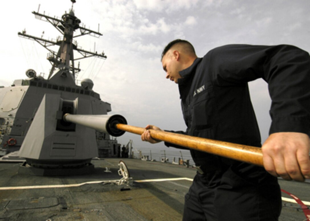 Navy Petty Officer 2nd Class Michael West cleans the barrel of an MK-45 5-inch, 54-caliber gun on the bow of the guided missile destroyer USS Shoup (DDG-86) as the ship operates in the South China Sea on April 18, 2006. West is a Navy gunnerís mate aboard the Arleigh Burke-class ship. 