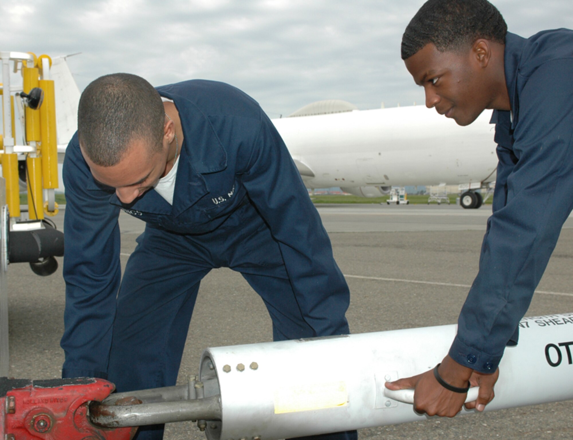 Seamen Alphonso Youngs and Jerome Mychael, both aircraft maintenance technicians, hook up a tow bar to a vehicle. The detachment has a supply warehouse on site for expedited parts.  This helps the detachment maintain its readiness level by cutting downtime waiting for parts. (U.S. Air Force photo by Staff Sgt. Raymond Hoy)



