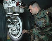 Tech Sgt. James Mazurek, 5th Maintenance Squadron, shows where a tow bar hooking up to the main landing gear of a B-52H Stratofortress can cause damage. (U.S. Air Force photo by Senior Airman Danny Monahan)
