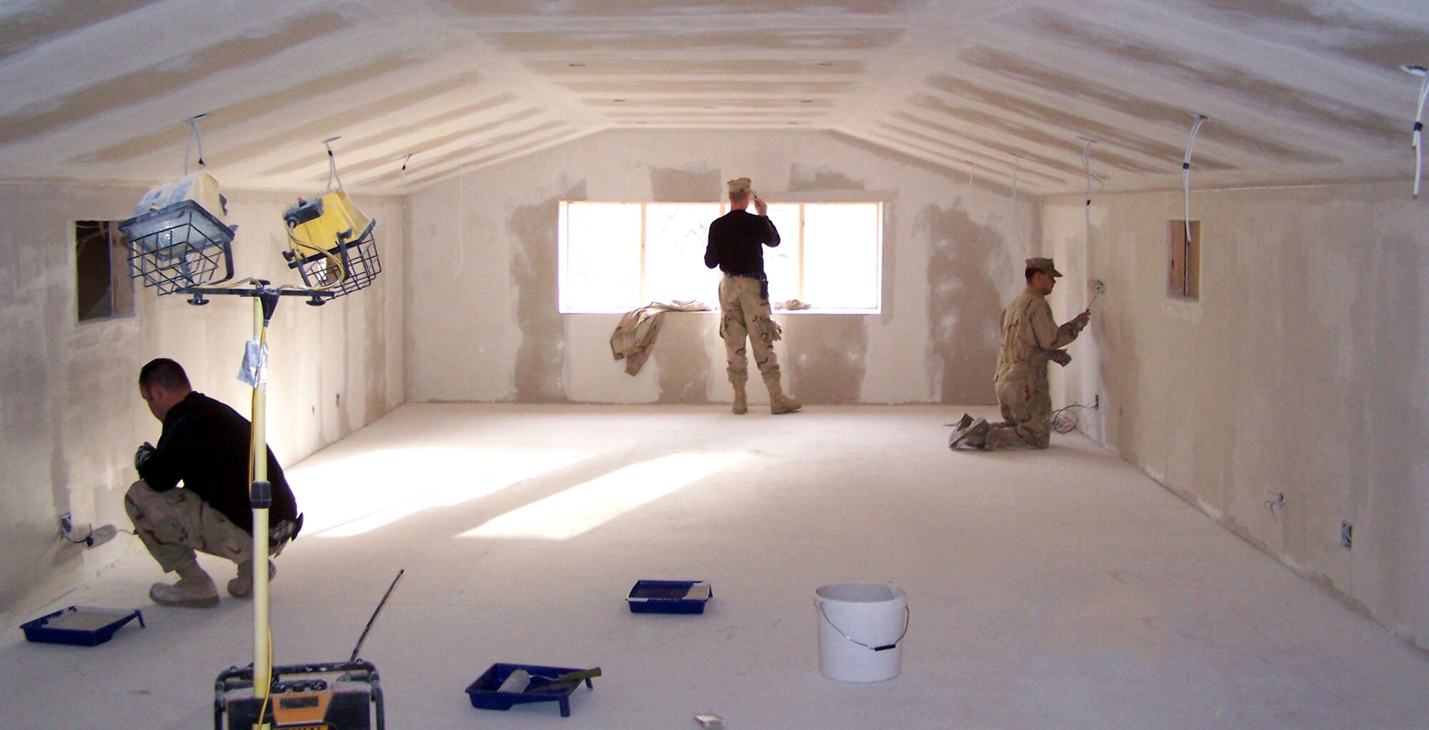 Airmen from the 376th Expeditionary Civil Engineer Squadron paint the walls of the commander's conference room on the newly built second floor of the wing headquarters at Manas Air Base, Kyrgyzstan. The building was built from the ground up inside an existing Soviet-era metal bunker by base Airmen, saving the Air Force more than half a million dollars. (U.S. Air Force photo/Master Sgt. Roger Williams)