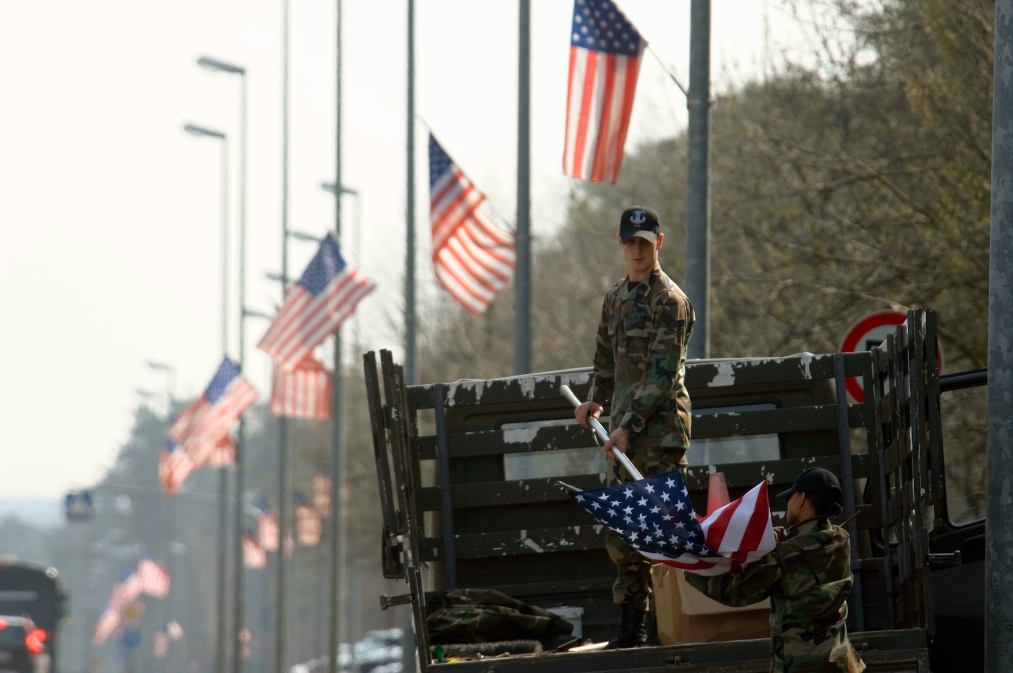 Senior Airman Shawn Duffy helps Staff Sgt. Davidad Langley attach a new flag for posting on the main drive at Ramstein Air Base, Germany, on Wednesday, April 19, 2006. Officials replace older flags periodically as part of the installation excellence program. Airman Duffy is a land and mobile radio technician and Sergeant Langley is a base information manager; both are with the 435th Communication Squadron. (U.S. Air Force photo/Master Sgt. John E. Lasky)