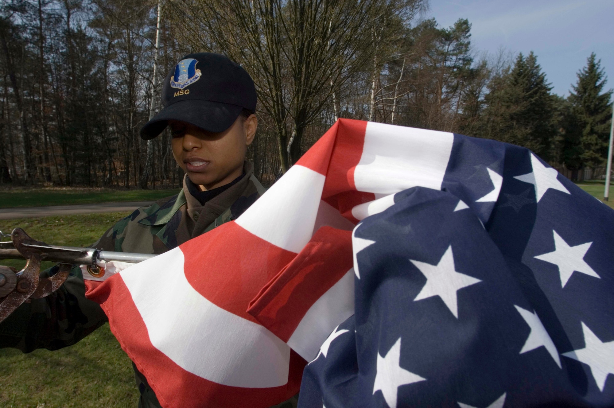 Staff Sgt. Davidad Langley unfurls a new flag for posting on the main drive at Ramstein Air Base, Germany, on Wednesday, April 19, 2006. Officials replace older flags periodically as part of the installation excellence program. Sergeant Langley is a base information manager with the 435th Communication Squadron. (U.S. Air Force photo/Master Sgt. John E. Lasky)