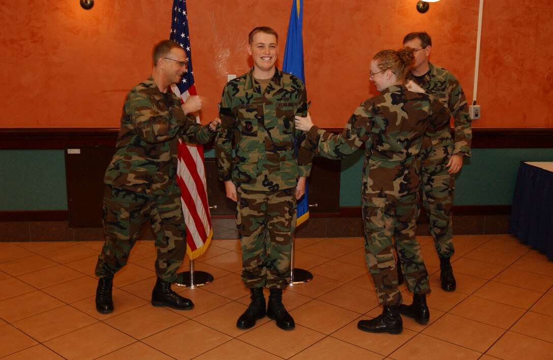AVIANO AIR BASE, Italy -- Col. Steven Schrader, 31st Fighter Wing vice-commander and Senior Airman Sarah Gregory, 31st FW, promote Airman 1st Class Jason Gregory, 31st Communications Squadron, to the rank of senior airman during the wing monthly promotion ceremony at the La Bella Vista Club Feb. 28.  Photo by Staff Sgt. Michael Holzworth, 31st CS. 