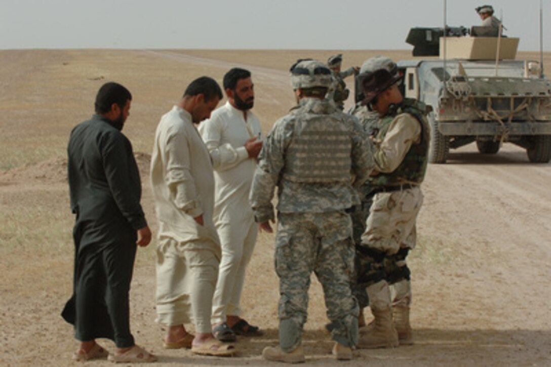 Soldiers from the U.S. Army's Alpha Battery, 3rd Battalion, 320th Field Artillery Regiment, 101st Airborne Division, check the identification of local men during a patrol near Tikrit, Iraq, on April 16, 2006. 