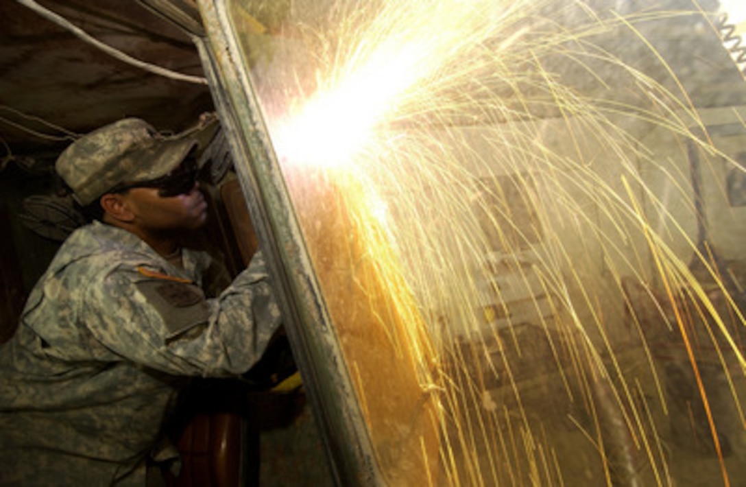 The torch of Army Sgt. Julius McLarin throws out a shower of sparks as he cuts armor plate at Forward Operating Base Marez in Mosul, Iraq, on April 18, 2006. McLarin is attached to the Brigade Support Battalion, 172nd Infantry Brigade. 