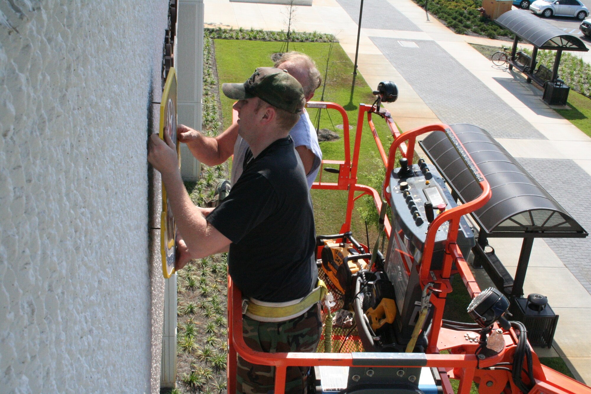 Staff Sgt. Peter Laing and Richard Lawson, 16th Civil Engineer Squadron, mount the Air Force Special Operations Command and 16th Special Operations Wing emblems on building 90210 Wednesday. The emblems were removed from the building for about two weeks to be refurbished and repainted.