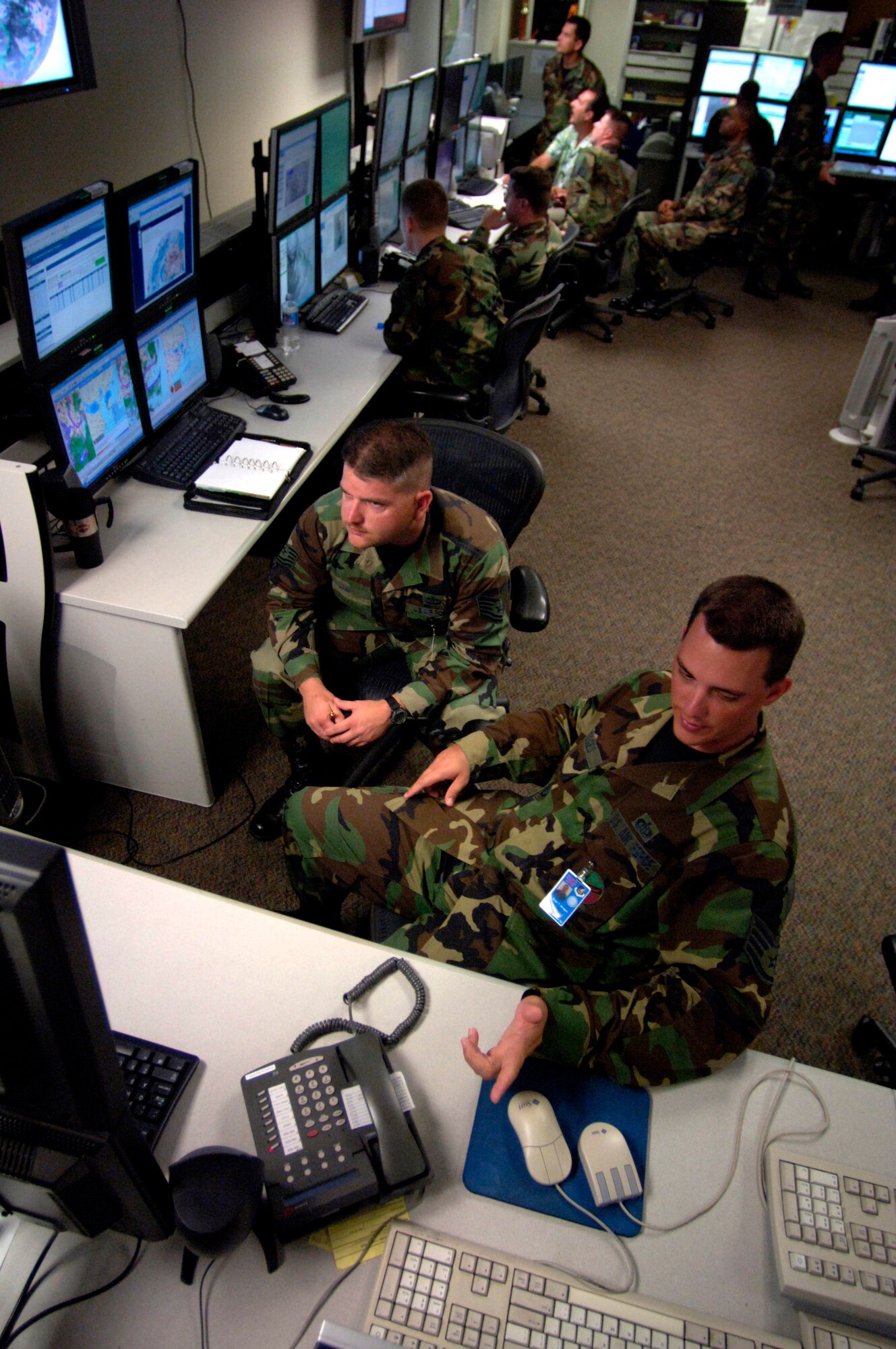 Staff Sgt. Brian Bridges and Tech. Sgt. Gary Lam discuss thunderstorms around Kadena Air Base, Japan, on the operations floor Tuesday, April 18, 2006, at Hickam Air Force Base, Hawaii. Sergeants Bridges and Lam are weather forecasters with the 17th Operational Weather Squadron, which provides Pacific Air Forces with tailored operational forecasts. (U.S. Air Force photo/Tech. Sgt. Shane A. Cuomo) 
