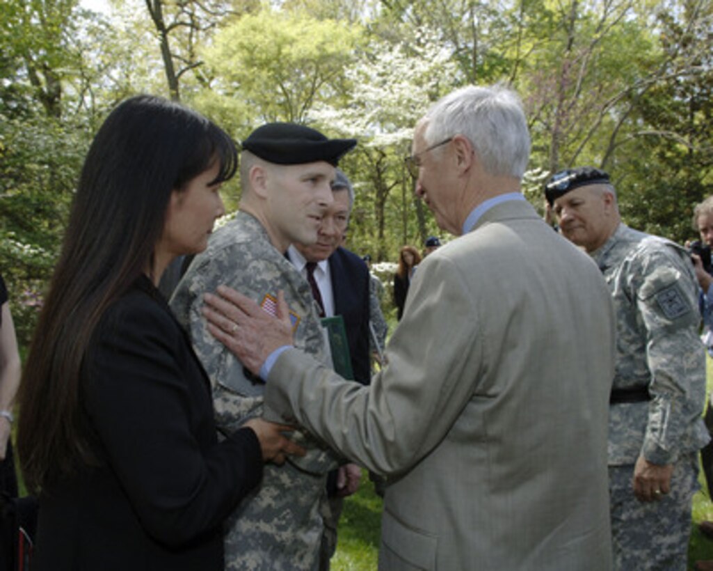 Deputy Secretary of Defense Gordon England presents his challenge coin to Army Spc. Maxwell Ramsey at President George Washington's Mount Vernon home in Mount Vernon, Va., on April 20, 2006. England and Vice chief of Staff of the Army Gen. Richard A. Cody (far right) co-hosted the ceremony to award the Purple Heart Medal to 7 Army soldiers wounded in Iraq. George Washington was the designer of the Purple Heart. 