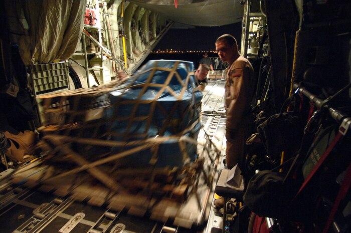 Senior Airman Robert Fisher pushes a cargo pallet into place while Senior Airman Matthew Marschall stands to the side in a C-130 Hercules on Wednesday, April 19, 2006. Airman Fisher is deployed from the 130th Airlift Wing at Charleston, W. Va., to the 447th Air Expeditionary Group. Airman Marschall is deployed from the 327th Airlift Squadron at Willow Grove Air Reserve Station, Pa., to the 746th Expeditionary Airlift Squadron. (U.S. Air Force photo/Master Sgt. Lance Cheung)