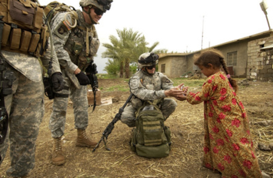 Army 1st Sgt. William Wilder (center) gives a handful of candy to an Iraqi girl during a break in foot patrol in Mahmodyah, Iraq, on April 12, 2006. Wilder and his fellow soldiers are attached to Delta Company, 1st Battalion, 502nd Infantry Regiment, 2nd Brigade, 101st Airborne Division. 