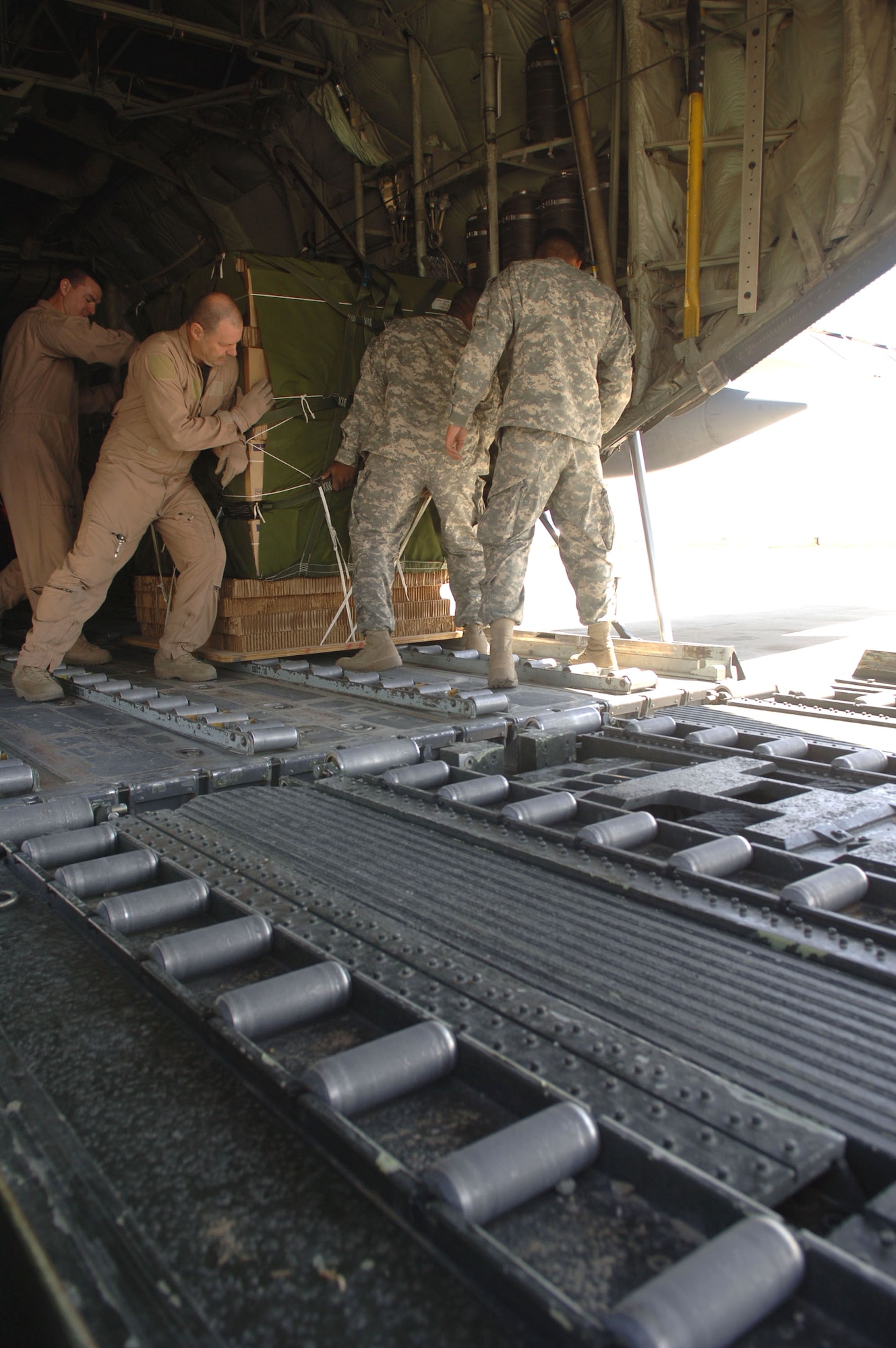 Airmen and Soldiers push a pallet onto a C-130 Hercules at Bagram Air Base, Afghanistan, on Saturday, April 15, 2006, in support of Operation Mountain Lion. (U.S. Air Force photo/Staff Sgt. Jennifer Redente) 

