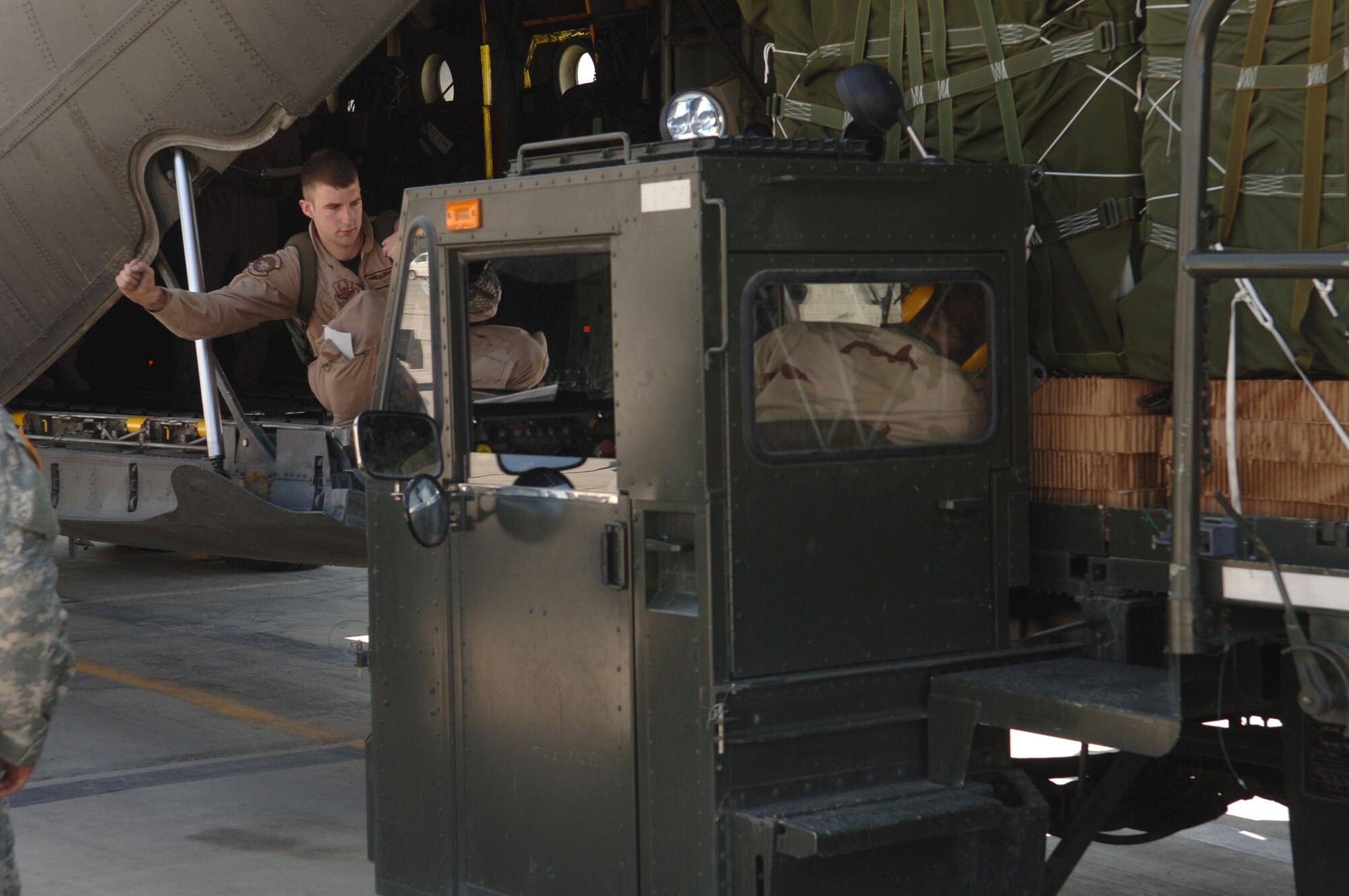 Senior Airman Travis Robotkay signals the driver of a cargo loader to stop during loading operations at Bagram Air Base, Afghanistan, on Saturday, April 15, 2006. Airman Robotkay is a loadmaster with the 774th Expeditionary Airlift Squadron and is deployed from Kulis Air National Guard Base, Alaska. (U.S. Air Force photo/Staff Sgt. Jennifer Redente)