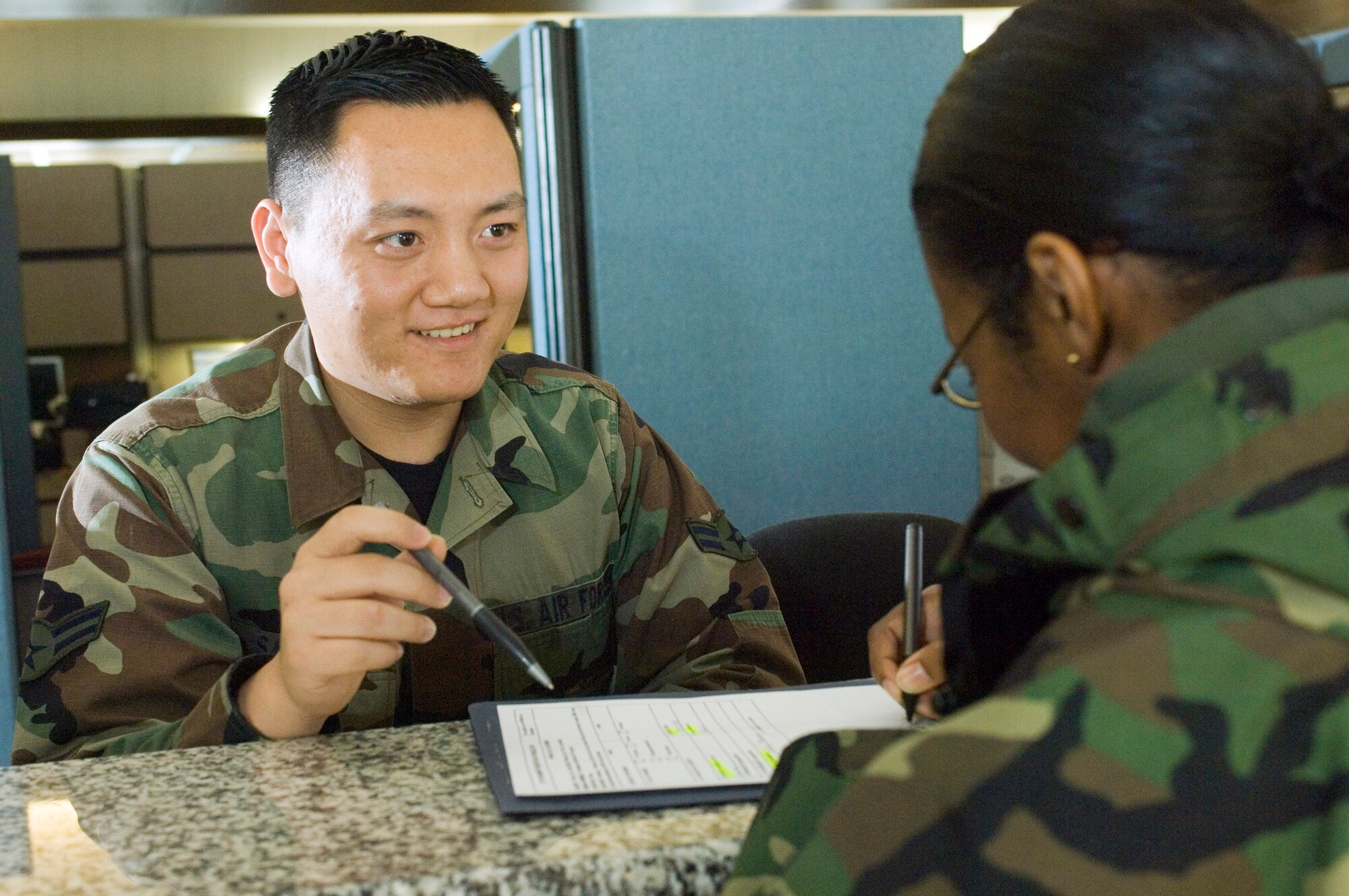 Airman 1st Class Michael Saechao clarifies an inprocessing form for a finance customer at Ramstein Air Base, Germany, on Tuesday, April 18, 2006. Airman Saechao is a financial customer service technician with the 435th Comptroller Squadron. Born in America to Thai parents, he joined the Air Force to travel. (U.S. Air Force photo/Master Sgt. John E. Lasky)
