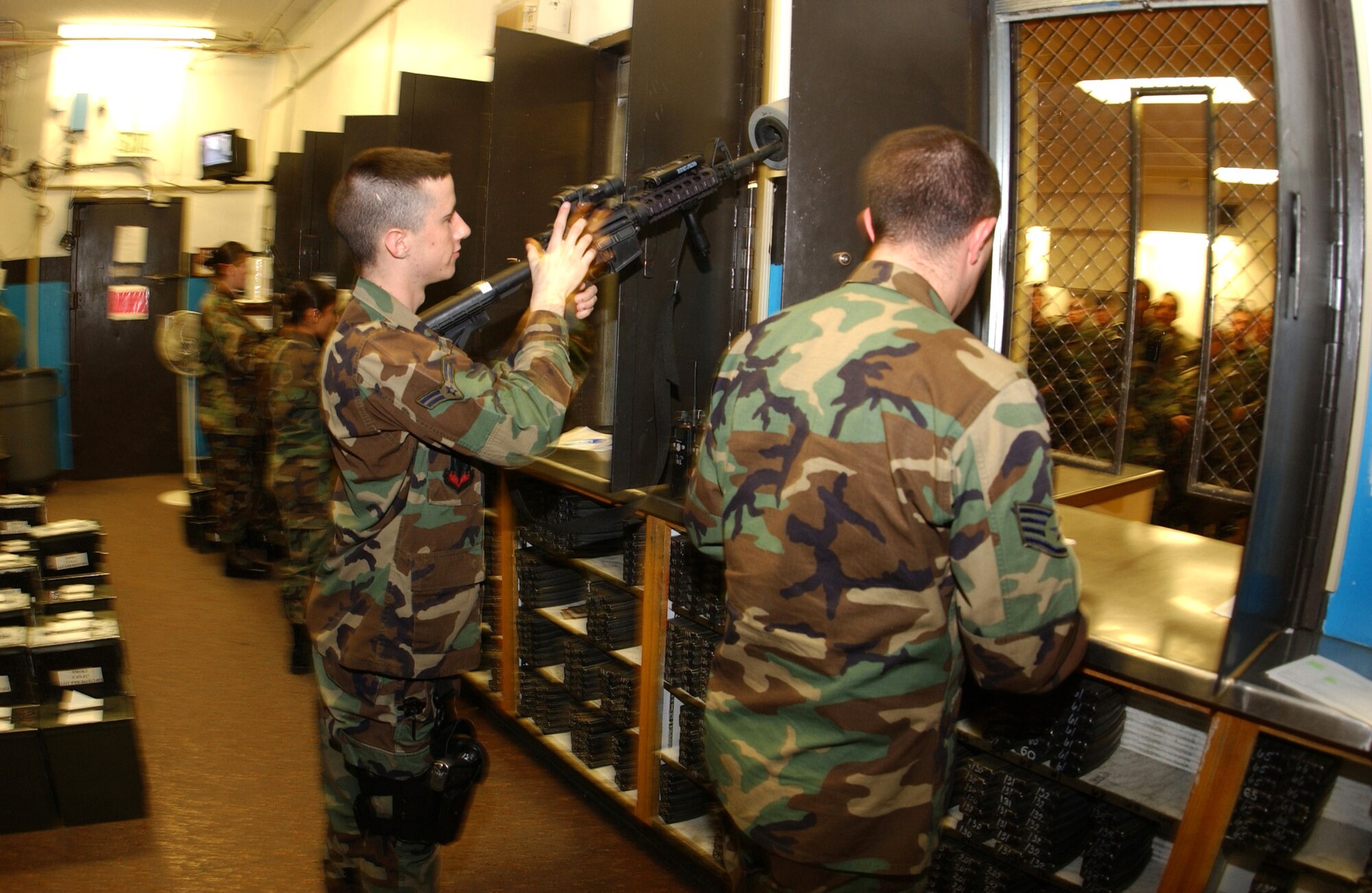 Airman 1st Class Matt Davis clears his weapon as other Airmen prepare supplies for issue before a shift change at the 5th Security Forces Squadron on Friday, April 21, 2006, at Minot Air Force Base, N.D. (U.S. Air Force photo/Staff Sgt. Jocelyn Rich) 
