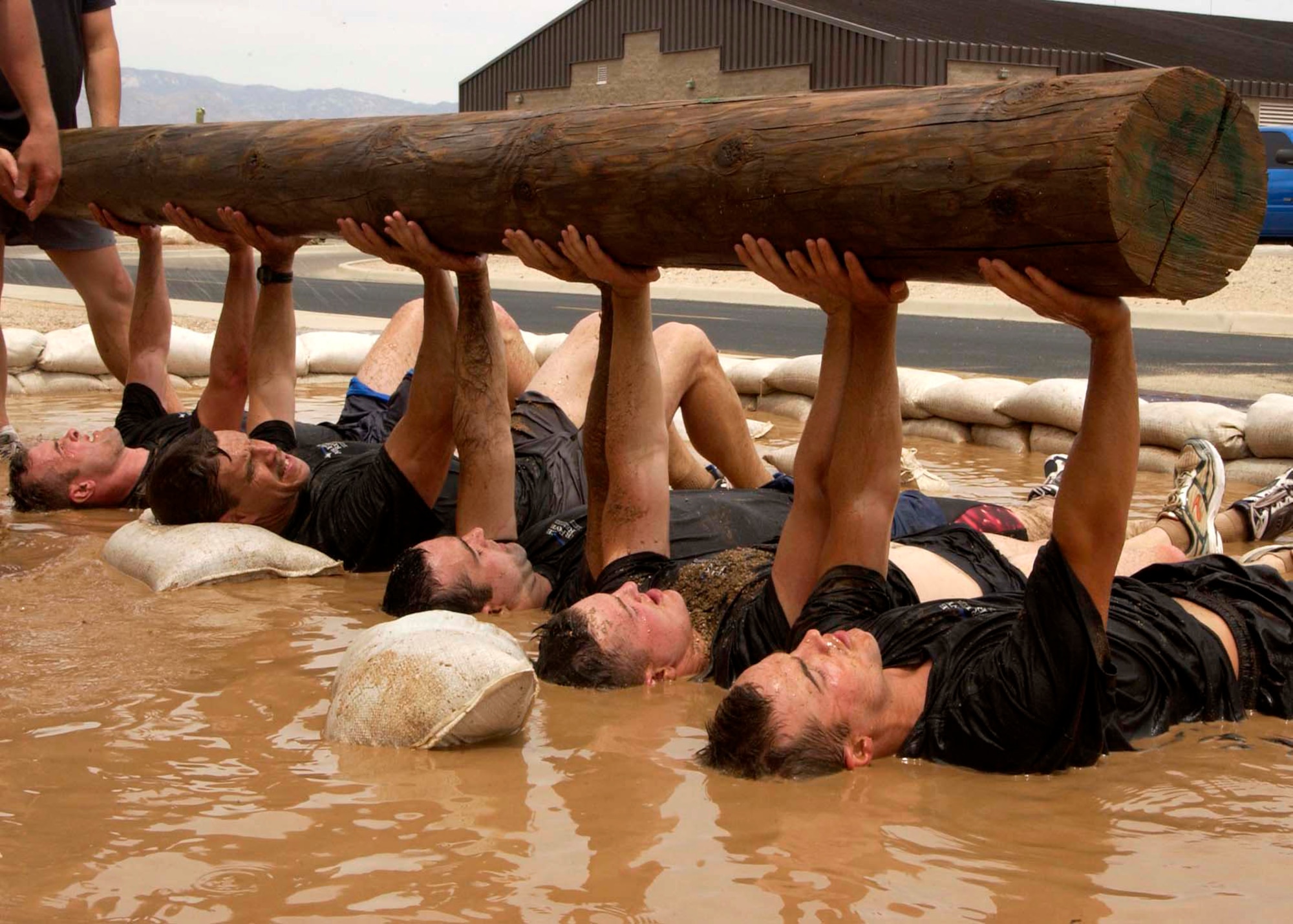 Military and civilian applicants taking part in the 306th Rescue Squadron pararescue screening hoist a wooden log while lying in a mud pit at Davis-Monthan Air Force Base, Ariz., on Friday, April 21, 2006. Applicants must pass a timed 3-mile run, 1,500-meter swim, calisthenics and other tasks before proceeding to the 10-week indoctrination course at Lackland AFB, Texas.  (U.S. Air Force photo/Airman 1st Class Veronica Pierce)