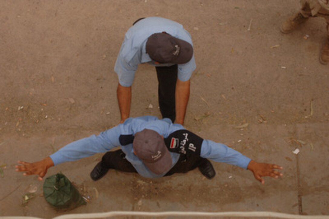 One Iraqi police officer pats down another for weapons as they participate in weapons safety and law enforcement training at the Al-Taji Police Station in Baghdad, Iraq, on April 17, 2006. U.S. Army soldiers from the 463rd Military Police Company, Camp Liberty, Iraq, are conducting the training. 