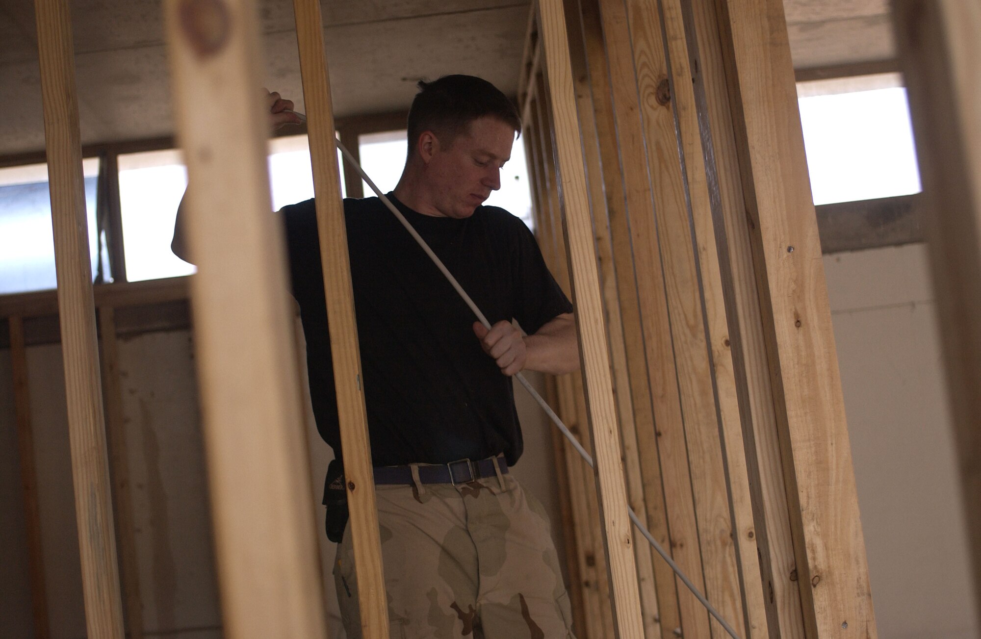 Senior Airman Brian Hess pulls wiring for the electric lines during renovation of an office building at Balad Air Base, Iraq, on Thursday, April 20, 2006. Airman Hess is with the 557th Expeditionary Red Horse Squadron. (U.S. Air Force photo/Tech. Sgt. Denise Rayder)


