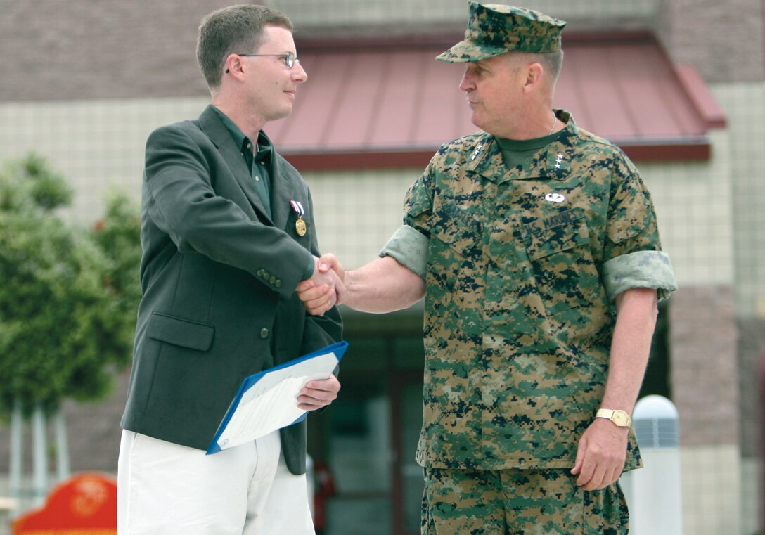 After receiving the first Defense of Freedom Medal awarded by the Marine Corps, Todd R. Alexander shakes hands with Lt. Gen. John F. Sattler, commanding general, 1st Marine Expeditionary Force. The Medal is the civilian equivalent of a Purple Heart.