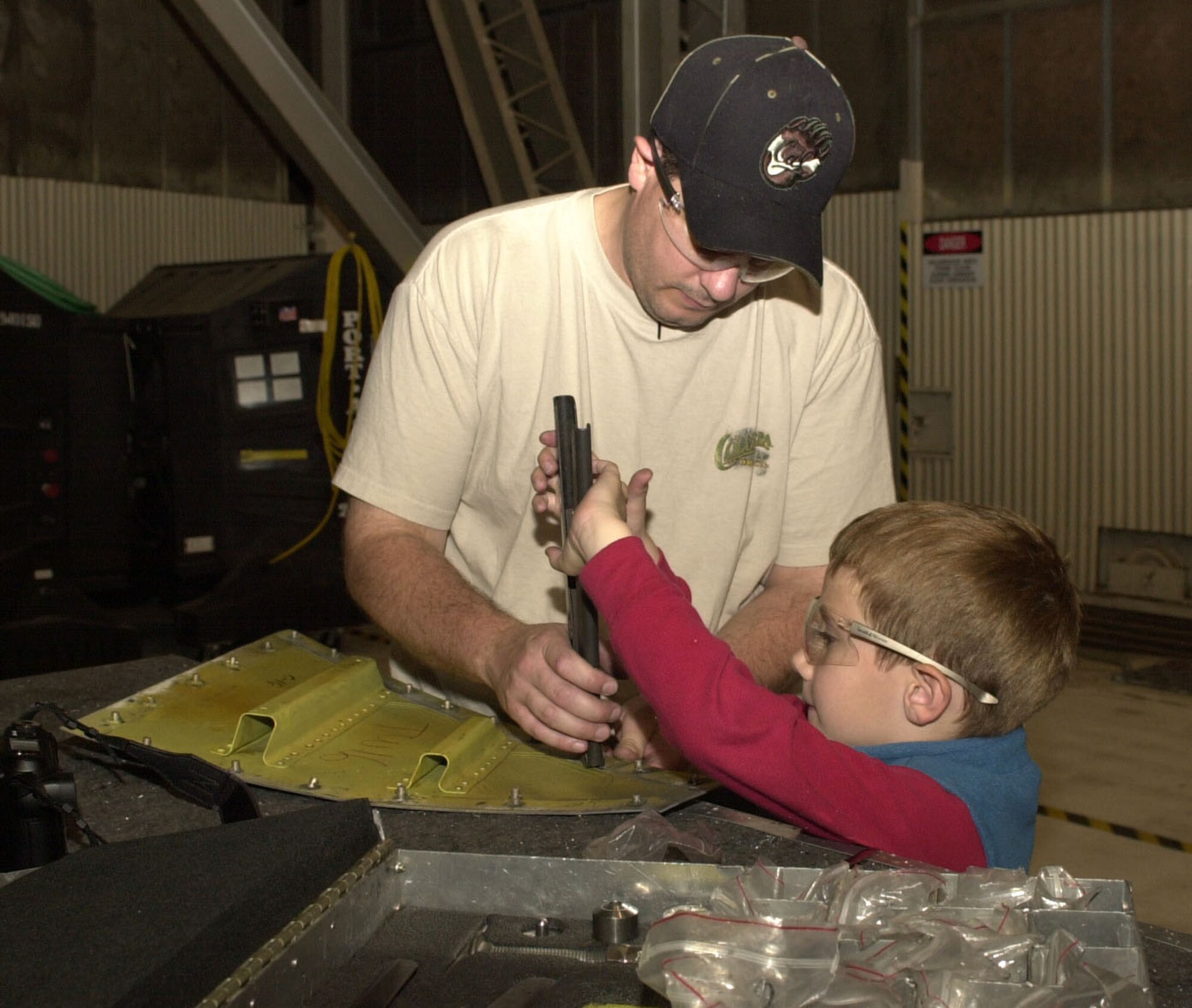 Air Reserve Technician, Staff Sgt. Pete Gibson, 940th Maintenance Squadron Structural Maintenance technician, and his son Tommy, 6, work together to install an air lock on a KC-135T panel at Beale Air Force Base, Calif.  Tommy came to work with his dad as part of the Bring your Daughters and Sons to Work Day April 27, 2006.  "He [Tommy] always asks me questions about what I did at work and I thought it would be good for him to see what I do," Sergeant Gibson said.  "He's very inquisitive and remembers what he sees."                               