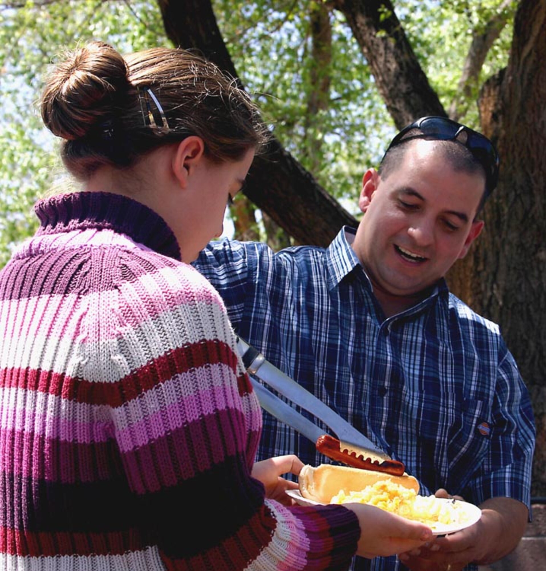 CANNON AIR FORCE BASE, N.M. - Tech. Sgt. Miguel Cruz, 27th Fighter Wing legal office, dishes out a hot dog to Madison Bridges, daughter of Chaplain (Capt.) Donald Bridges during a wing staff agency picnic at Unity Park April 21. About 75 Airmen and their families attended the outing. (U.S. Air Force photo by Janet Taylor-Birkey)