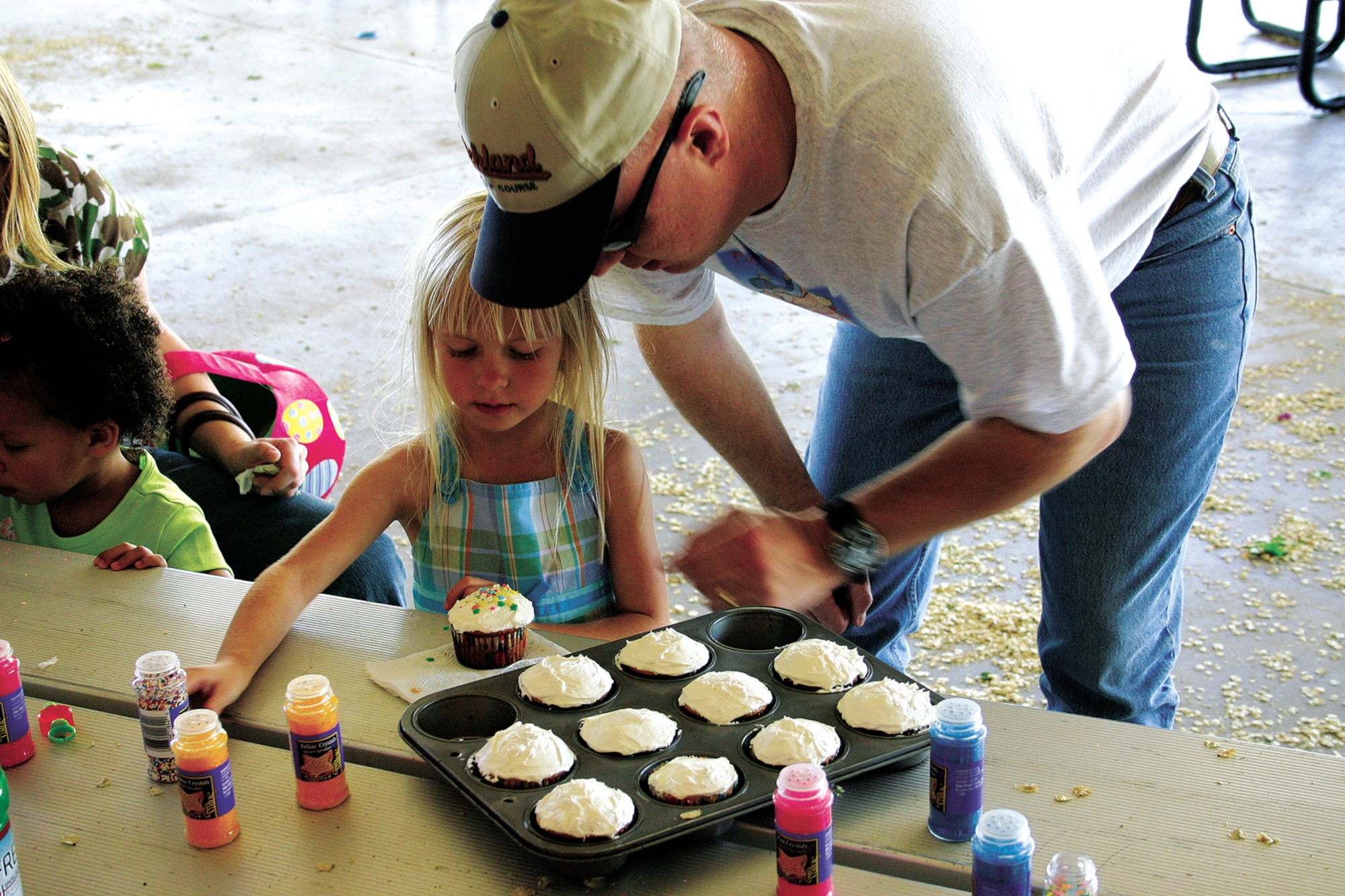 CANNON AIR FORCE BASE, N.M. - Tech. Sgt. Rodney Arnold, 27th Aeromedical Dental Squadron, helps his daughter Rachael, age 4, decorate her own cupcake under the pavilion at Unity Park. Children were invited to decorate cupcakes as well as decorating egg-shaped marshmallows. (U.S. Air Force photo by Staff Sgt. Craig Seals)