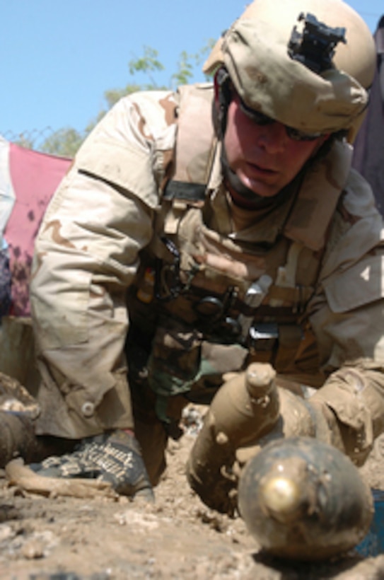 U.S. Navy Petty Officer 2nd Class William Schofer pulls ordnance buried in the mud near an abandoned building in Baghdad, Iraq, on April 20, 2006. Schofer and his fellow Explosive Ordnance Disposal Mobile Unit Six sailors recovered 340 anti-personnel mines and mortar shells from the site. 
