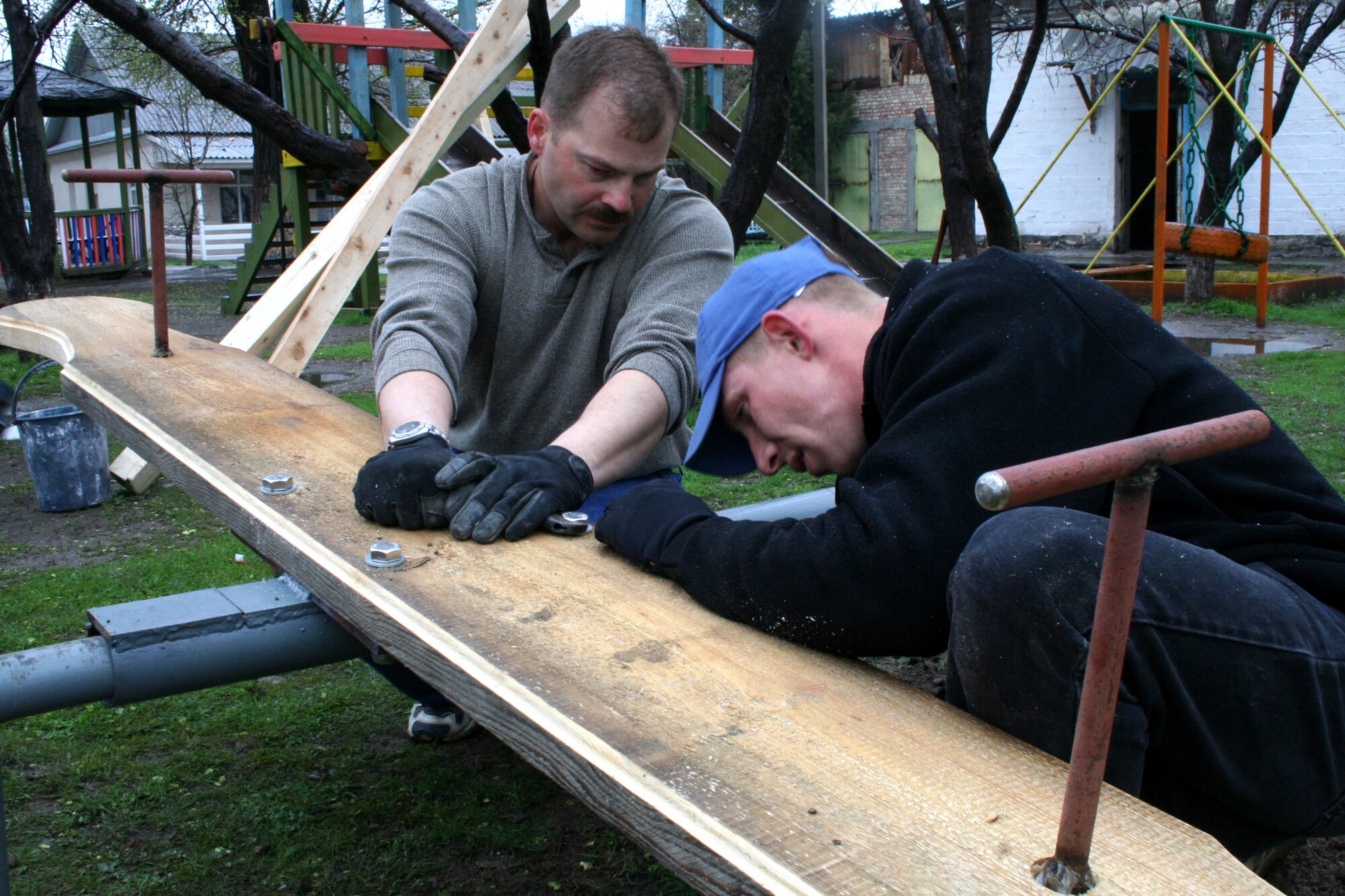 Master Sgt. Arthur Roy and Staff Sgt. Scott Williams install a seesaw at the Belovodsky Orphanage for children with special needs. Sergeant Williams helped construct the seesaw and has worked on other projects for the orphanage during his off-duty hours. The orphanage is in Belovodsky, Kyrgyzstan. (U.S. Air Force photo/Staff Sgt. Lara Gale)