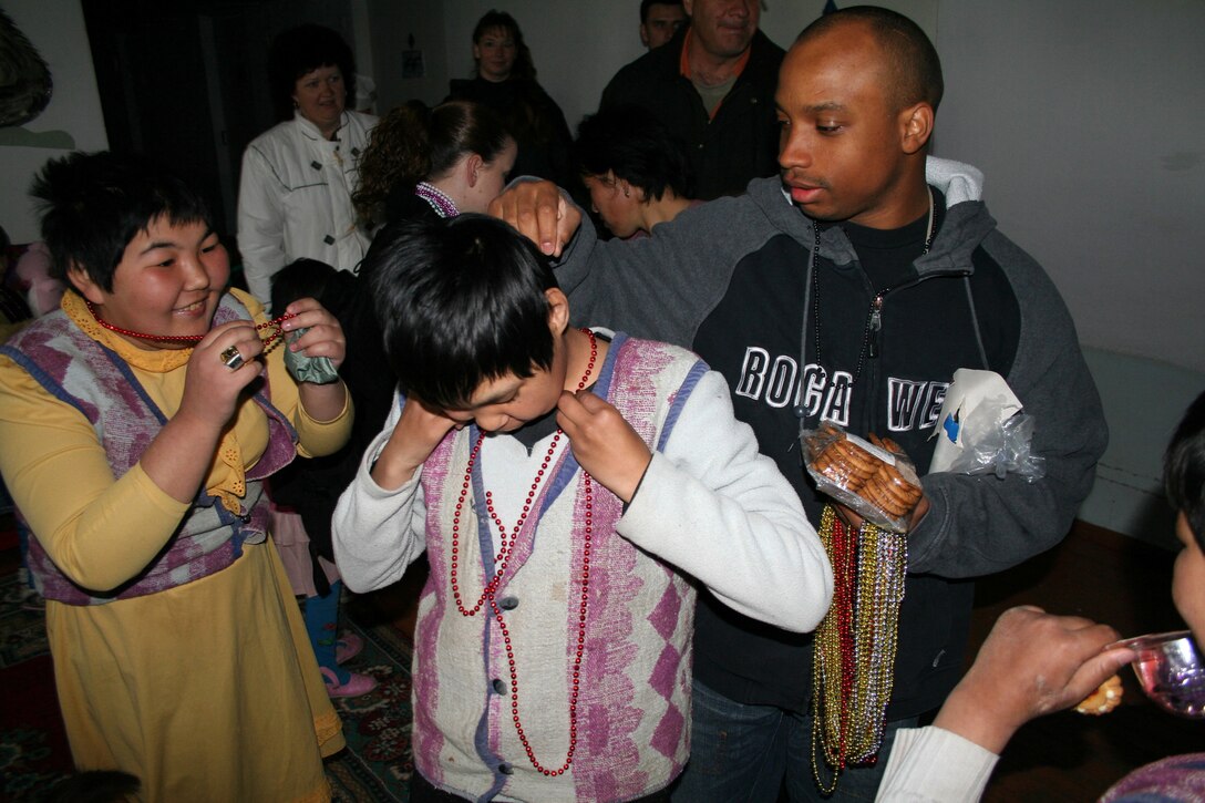 Senior Airman Tramell Johnson distributes bead necklaces at the Belovodsky Orphanage for children with special needs. Every week, he volunteers his day off to bring Airmen from Manas Air Base to the orphanage in Belovodsky, Kyrgyzstan, where they distribute treats, play with the children, and donate time and material to make needed repairs to the facility. (U.S. Air Force photo/Staff Sgt. Lara Gale)