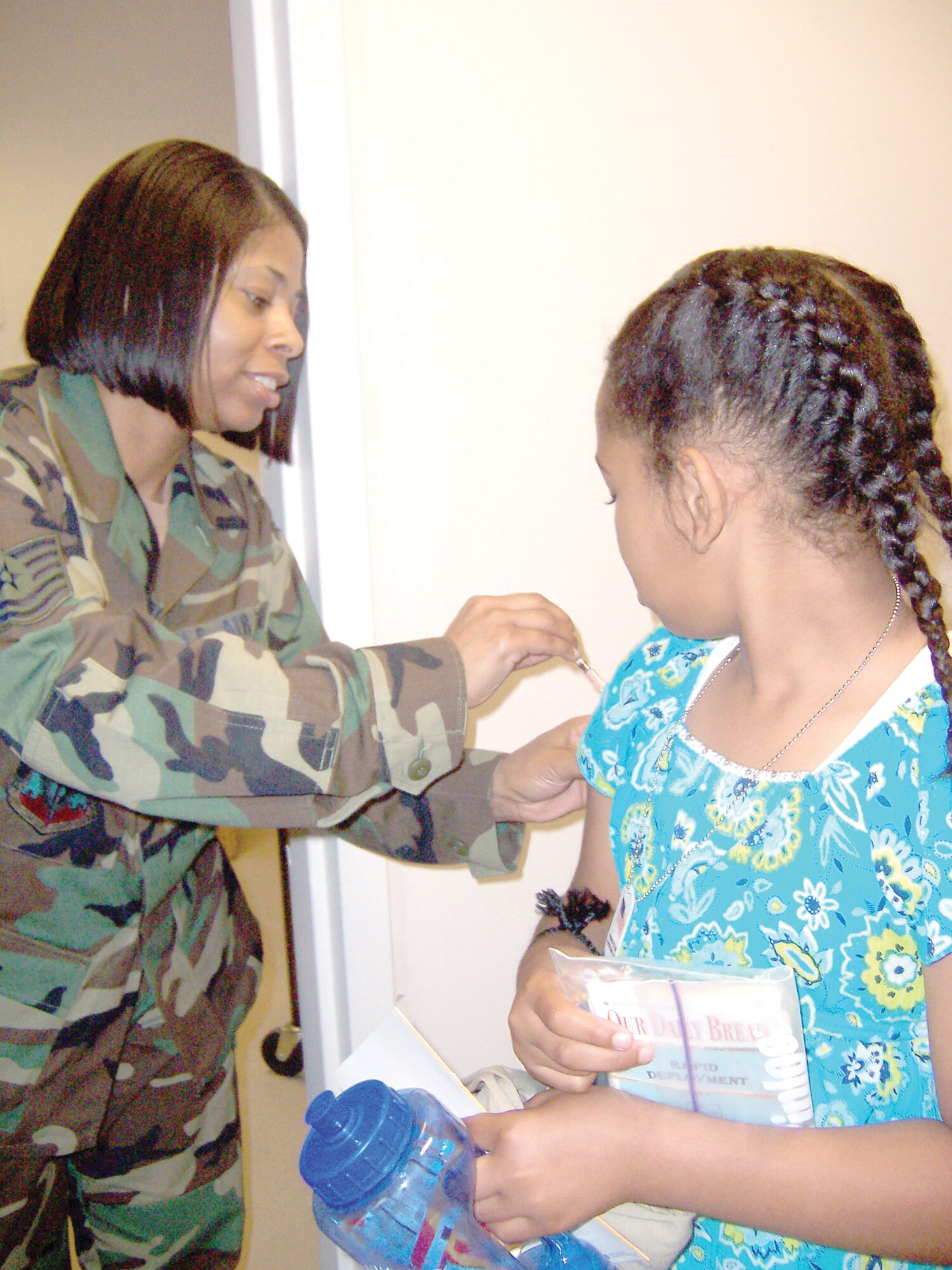 Tech. Sgt. Kimberly Robinson, 347th Medical Group Immunizations Clinic, gives Jasmine Henderson, daughter of 347th Mission Support Squadron Master Sgt. Bernadette Gregory, a “shot” to update her immunizations while processing through the deployment line. The Family Support Center Kids Deployment Line processed 50 children Saturday. (Photo by Senior Airman Leticia Hopkins)