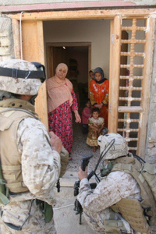 A U.S. Marine and a translator ask Iraqi women about activities in their neighborhood during a patrol in Ar Ramadi, Iraq, on April 19, 2006. The Marine is attached to Lima Company, 3rd Battalion, 8th Marine Regiment. 
