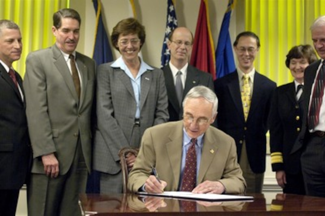 Senior executives of the National Security Personnel System look on as Deputy Secretary of Defense Gordon England (seated) signs the document authorizing the implementation of the first phase of the new National Security Personnel System during ceremonies at the Pentagon on April 28, 2006. 