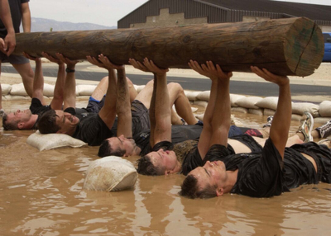 Pararescueman applicants bench press a wooden log in a mud pit during a screening process held by the Air Forceís 306th Rescue Squadron in Tucson, Ariz., on April 21, 2006. The applicants must pass a test that consists of a timed 3-mile run, 1500- meter swim, calisthenics, and other various tasks. 