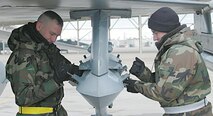 Senior Airmen Joshua Vanadore and Michael Brant, with the 421st Fighter Squadron weapons load crew, reconfigure bomb racks on an F-16 before the pilot takes the plane on temporary duty.