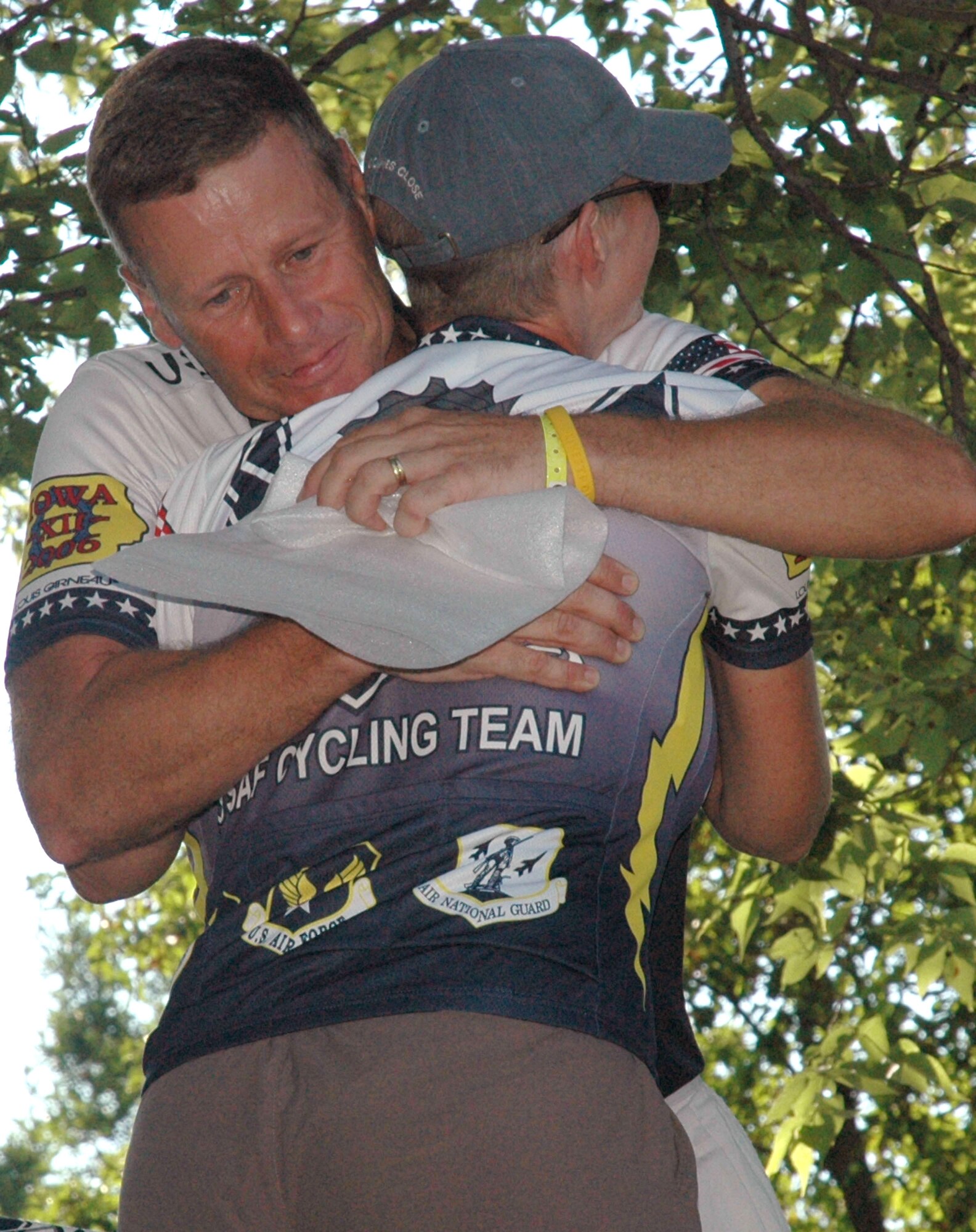 Col. John Clarke hugs Pamela Vineyard after giving her a plaque and photo of her with Lance Armstrong. The two cyclists met Mr. Armstrong at a reception in Newton, Iowa, during their ride with the Register's Annual Great Bike Ride Across Iowa, or RAGBRAI, July 27. Colonel Clarke is stationed at Randolph Air Force Base, Texas, and Ms. Vineyard is from Hill AFB, Utah. (U.S. Air Force photo/1st Lt. Kristen Duncan) 
