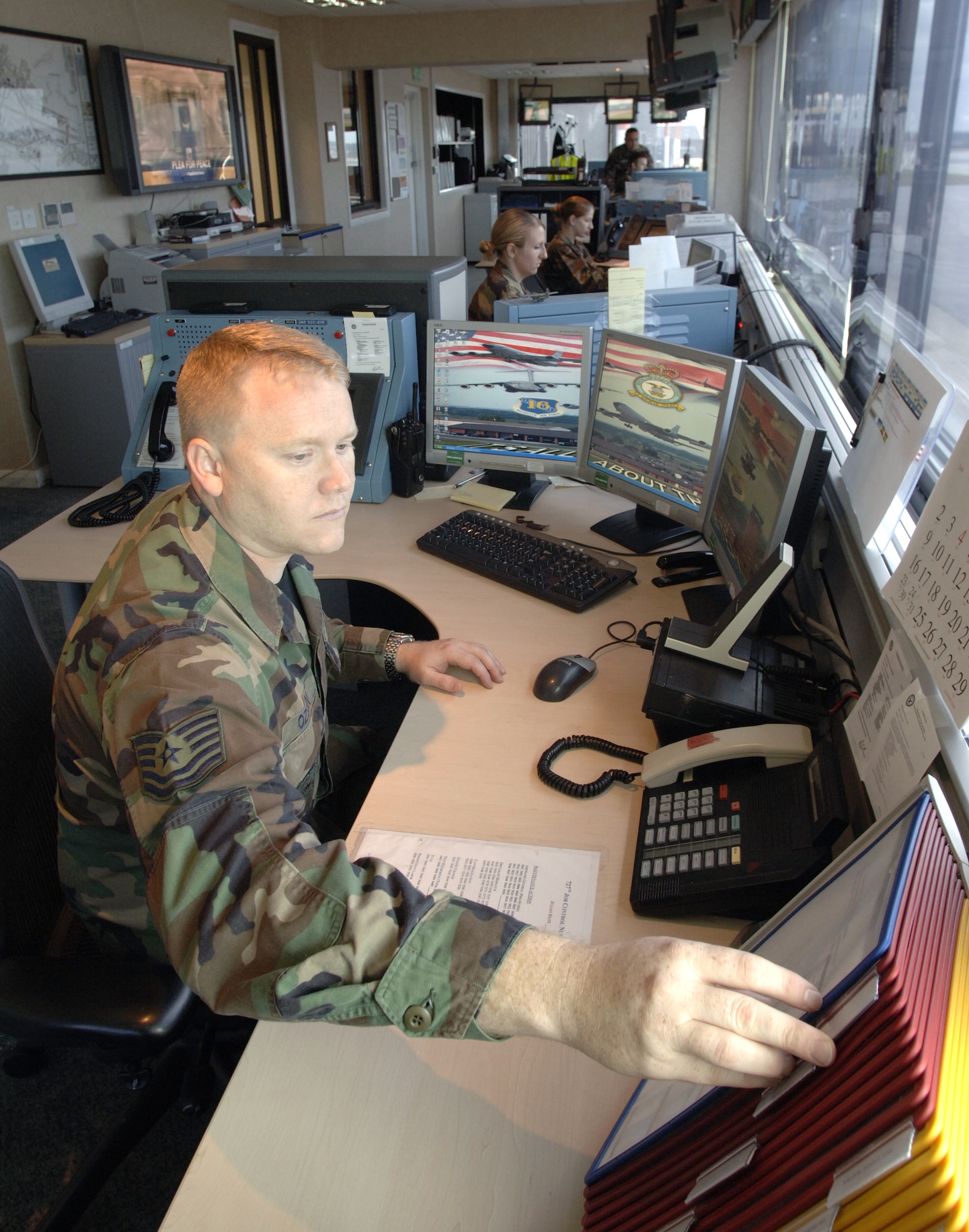 Tech. Sgt. T.J. Ozbun and (left to right) Senior Airman Erica Wells, Airman 1st Class Laura Gazda, Staff Sgt. Dan Scruton and Tech. Sgt. Raymond Sanchez work at the combined maintenance operations and air terminal operations center at Royal Air Force Mildenhall, England, on July 31. The crew controls the movement of missions, passengers, cargo, aircraft and maintenance for transient aircraft at Mildenhall. (U.S. Air Force photo/Master Sgt. Lance Cheung)