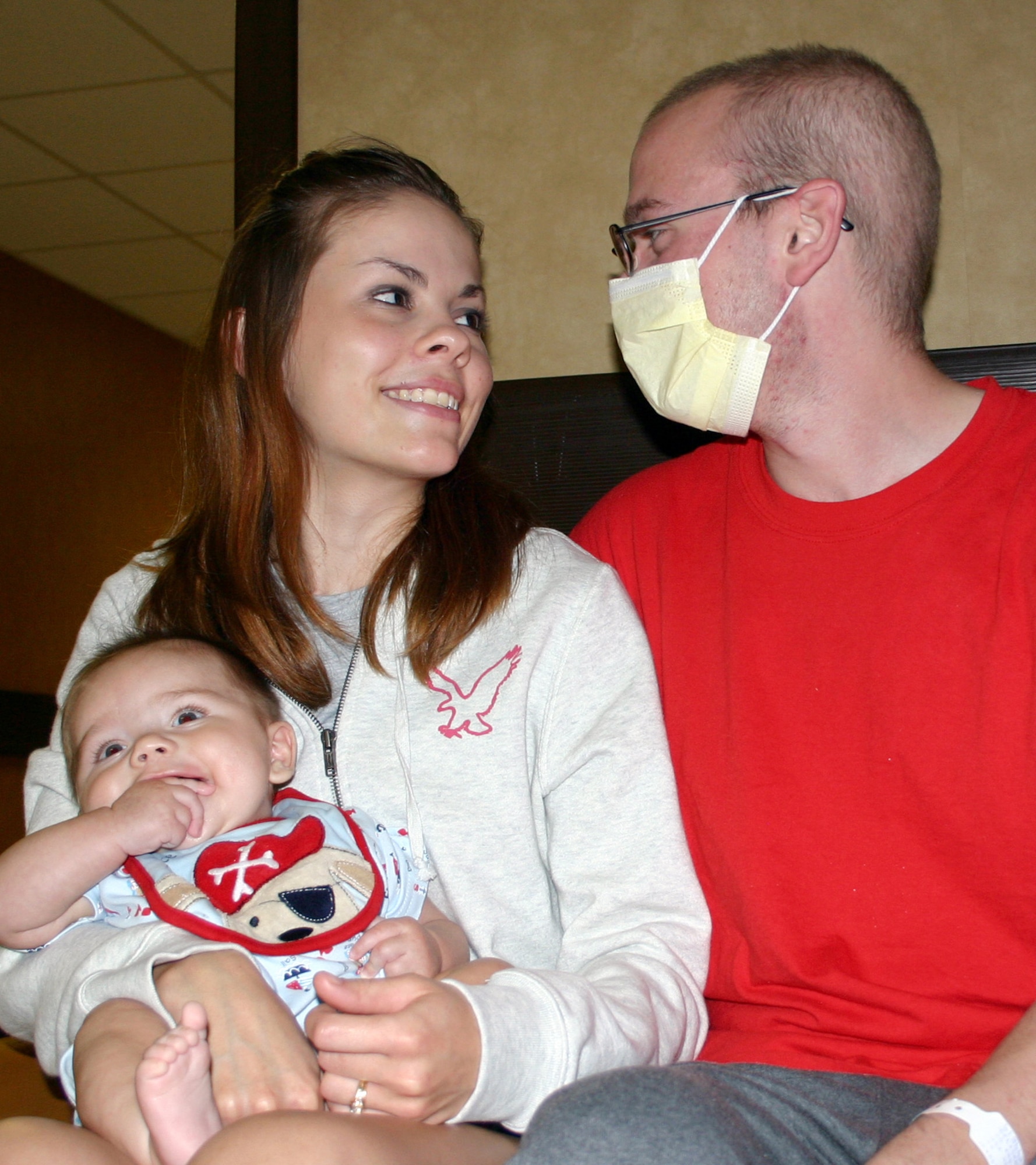 Army Sgt. Joe DeLashmutt visits with his wife, Melissa, and son, Austin, at the Fisher Bone Marrow Transplant Unit at Wilford Hall Medical Center at Lackland Air Force Base, Texas, on July 10. Sergeant DeLashmutt was diagnosed with leukemia while deployed to Iraq. He is wearing a surgical mask and is not able to hold his son until the new marrow he received has replenished his immune system. (U.S. Air Force photo/Master Sgt. Kimberly Spencer)

