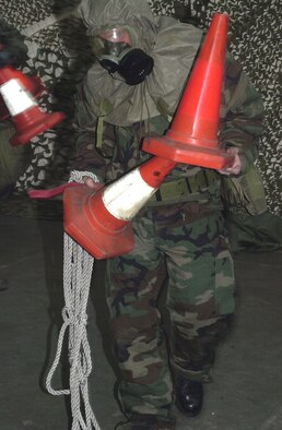 Senior Airman Thomas Nightingale, 100th Aircraft Maintenance Squadron crew chief, simulates cordoning off a contaminated vehicle during the exercise portion of a Chemical, Biological, Radiological, and Nuclear Defense Training class held here. (U.S. Air Force photo by Geoff Janes)