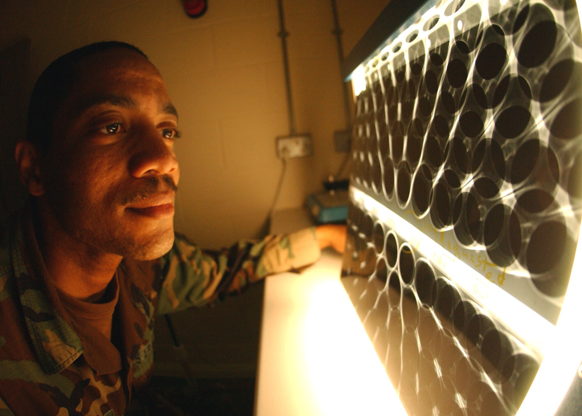 Staff Sgt. Corey Fletcher, 100th Maintenance Squadron Fabrications Flight, non-destructive inspection specialist, looks over an X-ray film of an MH-53 Pave Low helicopter engine air particle separator June 20. NDI specialists detect structural flaws, cracks, defects and foreign object damage in aircraft parts by using X-rays and fluorescent green penetrant. The cracks are usually invisible to the naked eye, but the NDI team finds them and make sure affected parts are taken out of service immediately. (U.S. Air Force photo by Staff Sgt. Tyrona Pearsall)