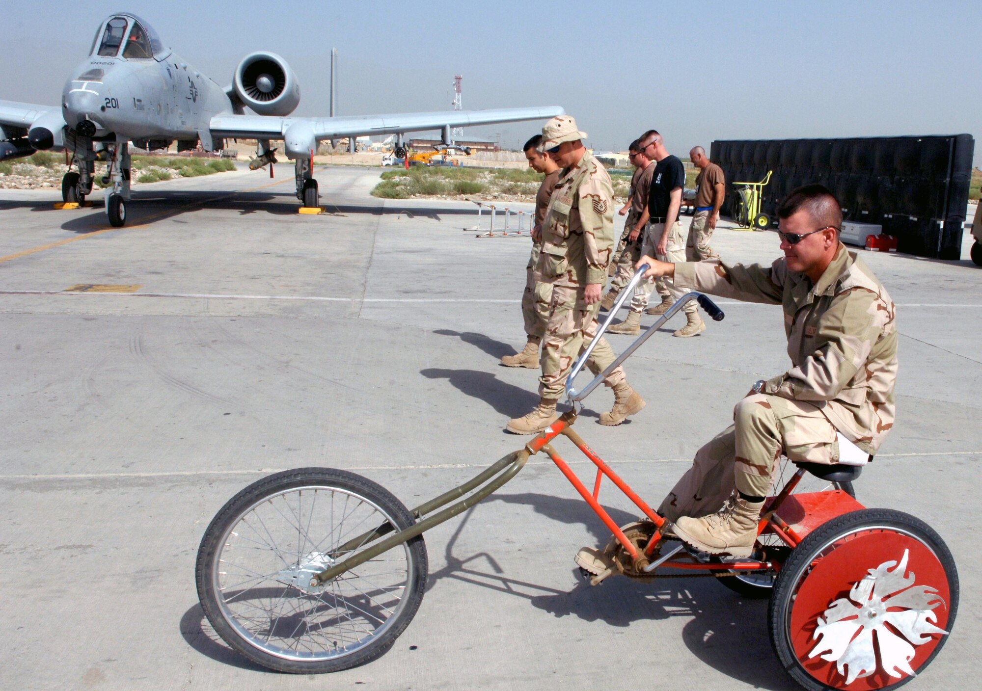 Capt. Jason Weiser rides a bike during a foreign object damage walk Aug. 1 on the flight line at Bagram Airfield, Afghanistan. The captain's section built the bike while they've been deployed here. Captain Weiser is a member of the 455th Expeditionary Maintenance Group. (U.S. Air Force photo by Master Sgt. Orville F. Desjarlais Jr.)