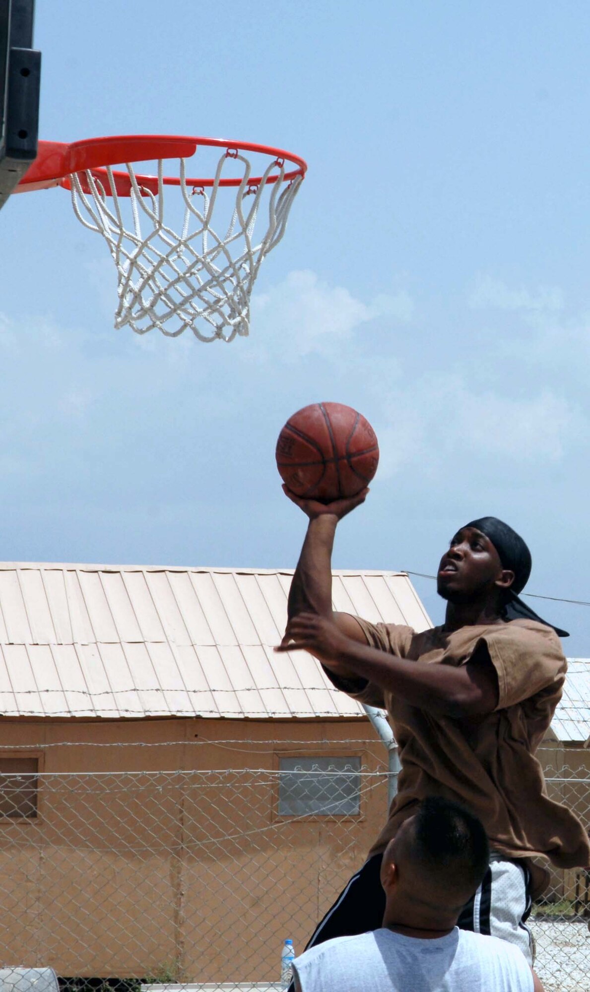 Darryl Sanders, a player for Mixed Batch, goes in for an easy layup. Not so easy was winning the four-on-four basketball tournament here July 30.  The Security Forces team came back from the loser's bracket, but in the end lost to Mixed Batch in overtime, 11-10. The field consisted of six teams in a double-elimination tournament. Sanders is a member of the 455th Expeditionary Maintenance Group. (U.S. Air Force photo by Master Sgt. Orville F. Desjarlais Jr.)

 
