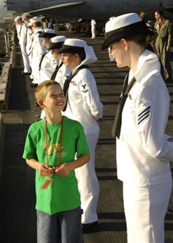 U.S. Navy Seaman Buckingham chats with her family member while she and other sailors from the USS Abraham Lincoln (CVN-72) man the rails during Lincoln's departure from Pearl Harbor, Hawaii, for a Tiger Cruise on July 29, 2006.  The Tiger Cruise allows families and friends of the crew an opportunity to experience life at sea by embarking aboard the ship for a week.  