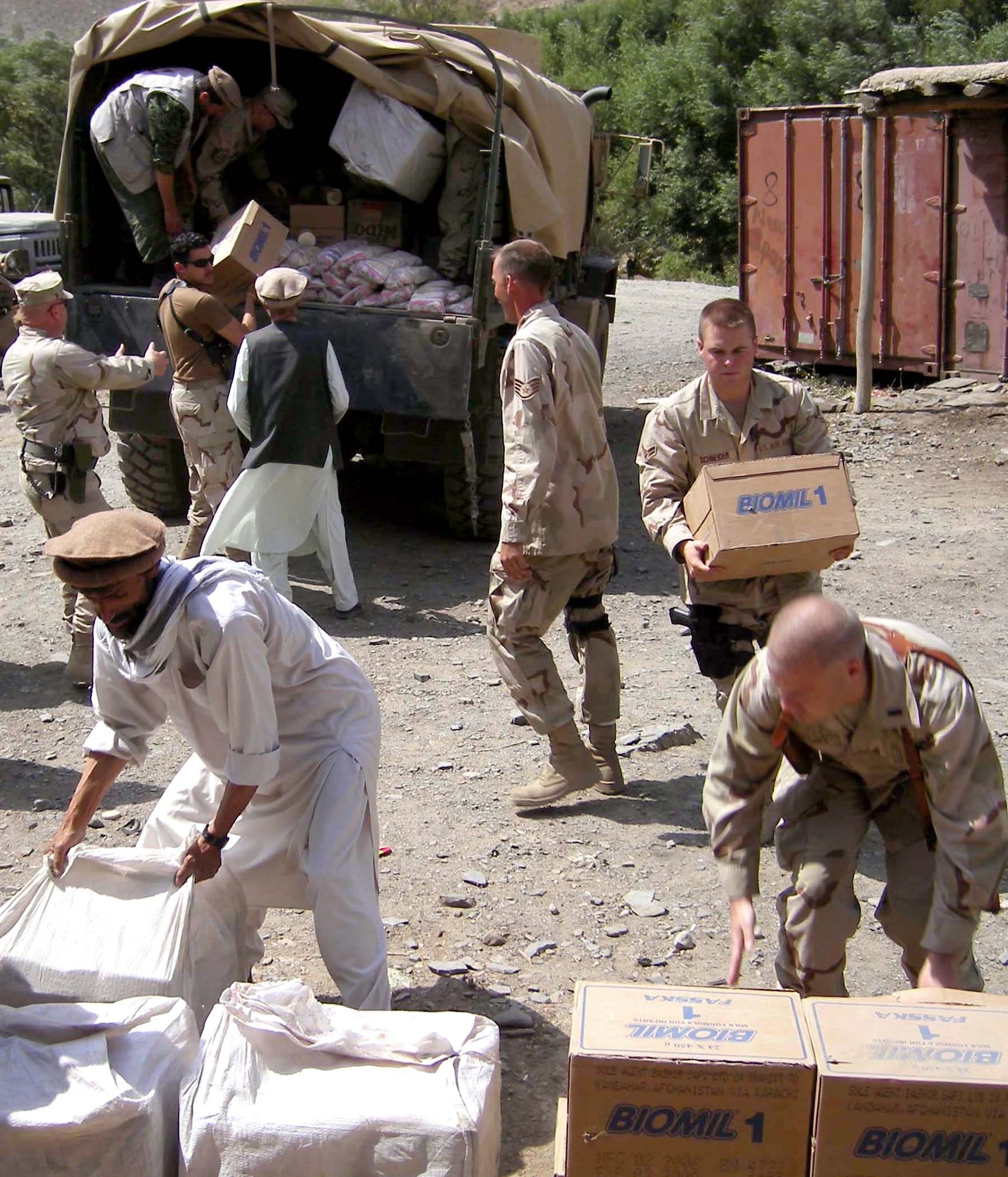Members of the Panjshir Provincial Reconstruction Team and volunteers unload a 5-ton truckload of humanitarian assistance food supplies near Abdara, Afghanistan, on July 30. More than 180 Afghan locals are building a road by hand to connect three villages to the main road across the Panjshir River. Governor Haji Bahlol requested assistance for workers who are unable to provide for their families while building the road. The PRT also plans to provide tool kits consisting of shovels, picks, hammers and other hand tools to assist with the project. (Courtesy photo/Shahla Hammond) 