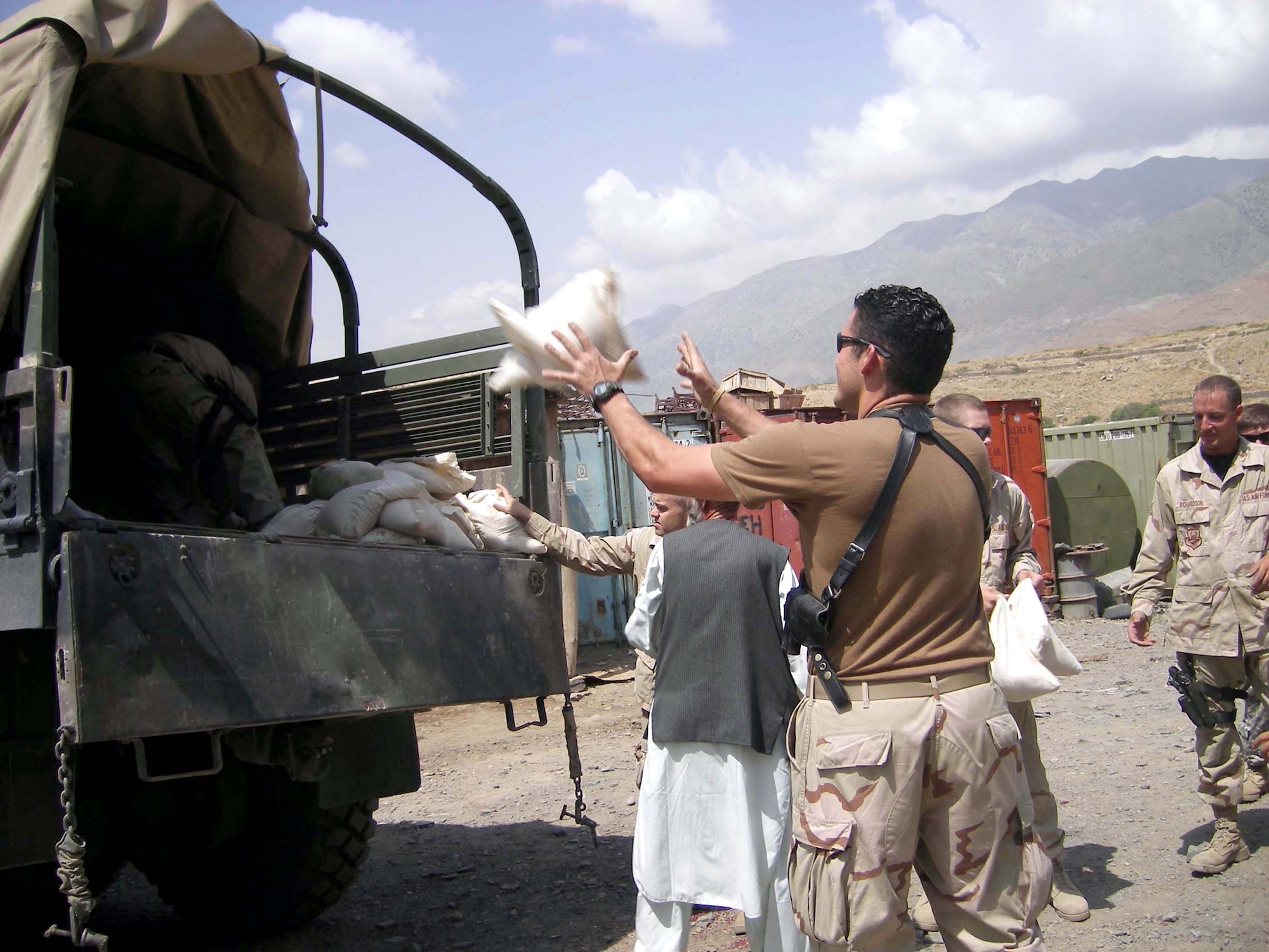 Senior Airman Dennis Martinez catches a bag of dried beans as members of the Panjshir Provincial Reconstruction Team unload a 5-ton truckload of humanitarian assistance food near Abdara , Afghanistan, on July 30. Airman Martinez is deployed from Tinker Air Force Base, Okla. (U.S. Air Force photo/Capt. Joe Campbell)
