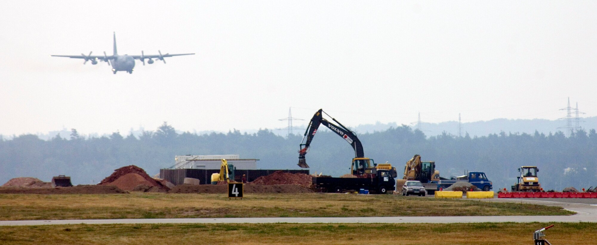 A C-130 Hercules uses the south runway as construction continues on the north runway at Ramstein Air Base, Germany, on July 28. The north runway will be extended 1,000 feet, allowing heavy air transports to take off fully loaded. The work began in mid-April and is one week ahead of the Jan. 1 completion date. (U.S. Air Force photo/Master Sgt. John E. Lasky) 
